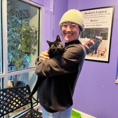 Woman holding black cat after adoption